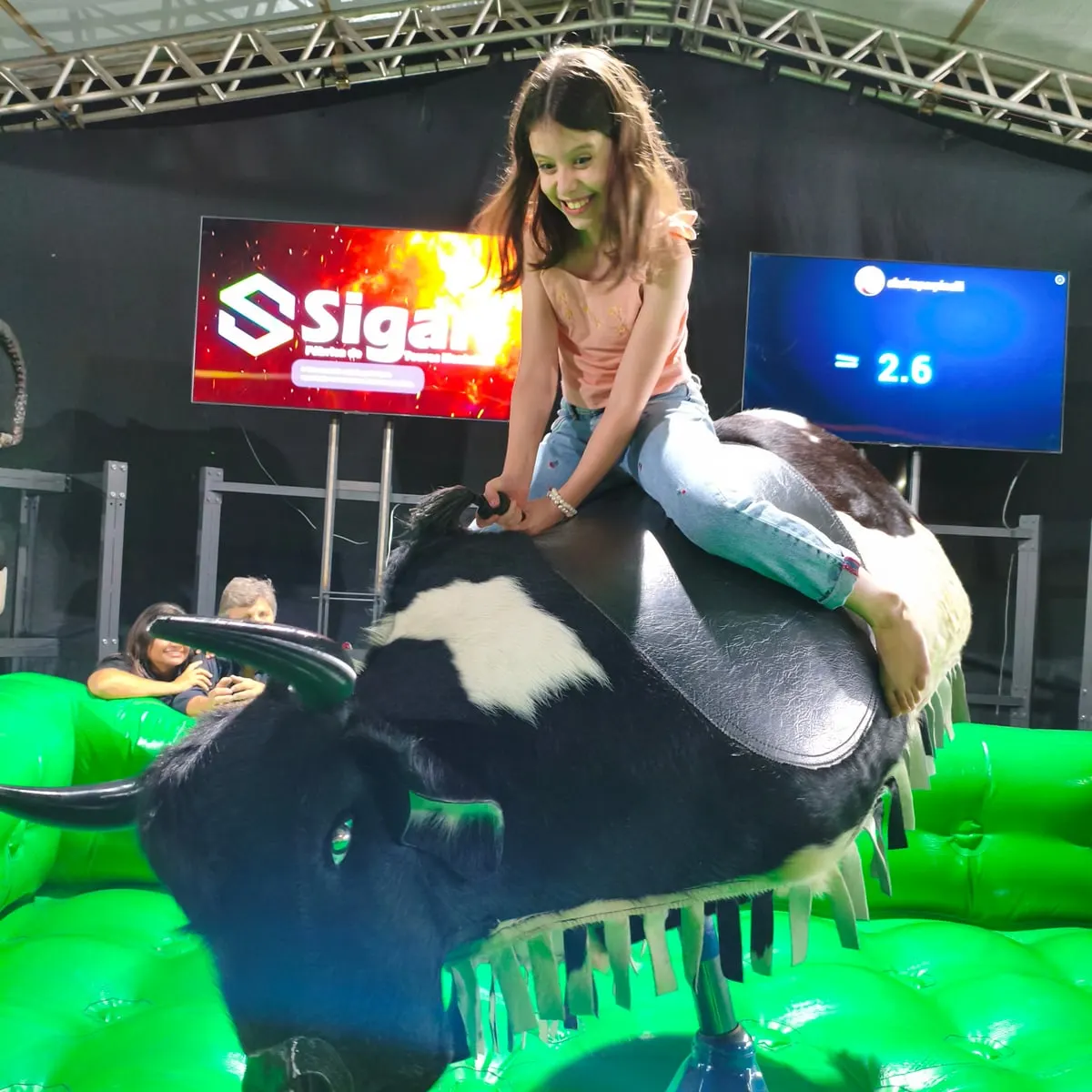 Menina sorrindo montada no 9 Pulos, com 2,6 segundos no cronômetro do telão